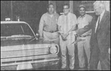 A group of men standing next to a car

Description automatically generated