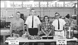 A group of people standing behind a counter with food on it

Description automatically generated with low confidence
