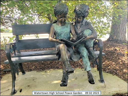 A statue of two children sitting on a bench

Description automatically generated